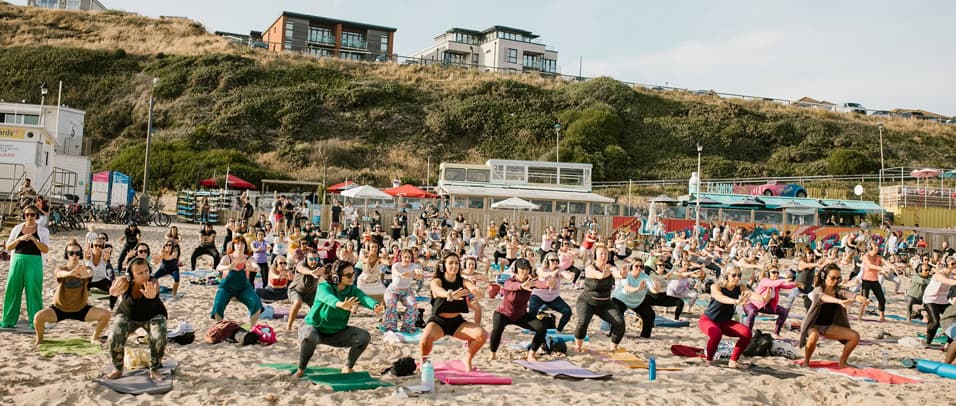 Hundreds of people taking part in a wellbeing session on the sand at SOBO Beach